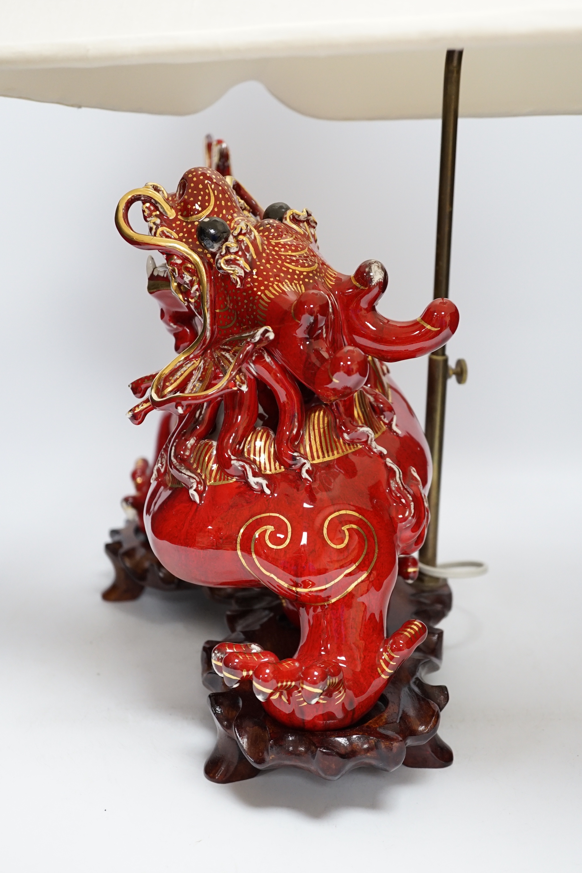A modern Chinese red and gilt glazed ceramic 'dragon' table lamp on carved wood stand with shade, total height 68cm